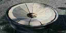 A circular stone forge that slopes toward a hole in its center.