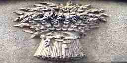 A carving of wheat tied together with a straw braid on a gravestone.