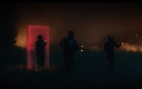Three soldiers carrying guns walk out of a rectangular gelatinous glowing portal through a forest at night. Portal is red-colored.