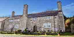 A a medieval stone brick building with windows and chimneys in Wales.